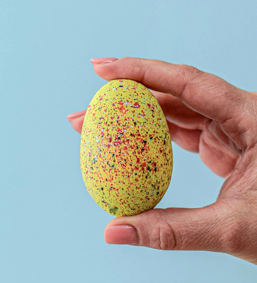 An adult holding one of the eggs from the Bumbu stegosaurus egg set.