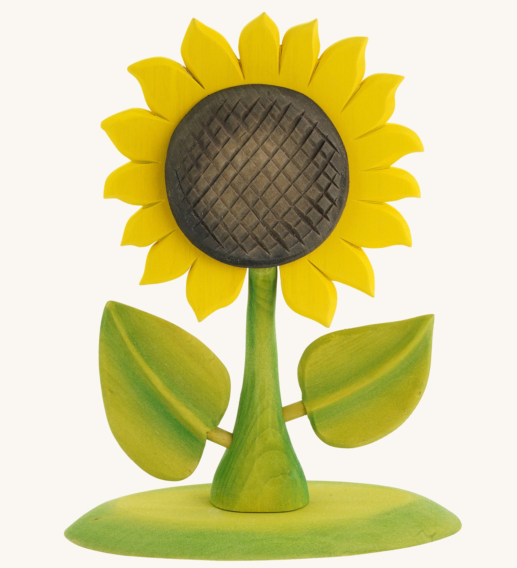 Bumbu Large Wooden Sunflower, Hand Crafted and Hand Painted. A Large yellow Sunflower with green stalk and leaves, on a green wooden base being held in a hand. On a blue background