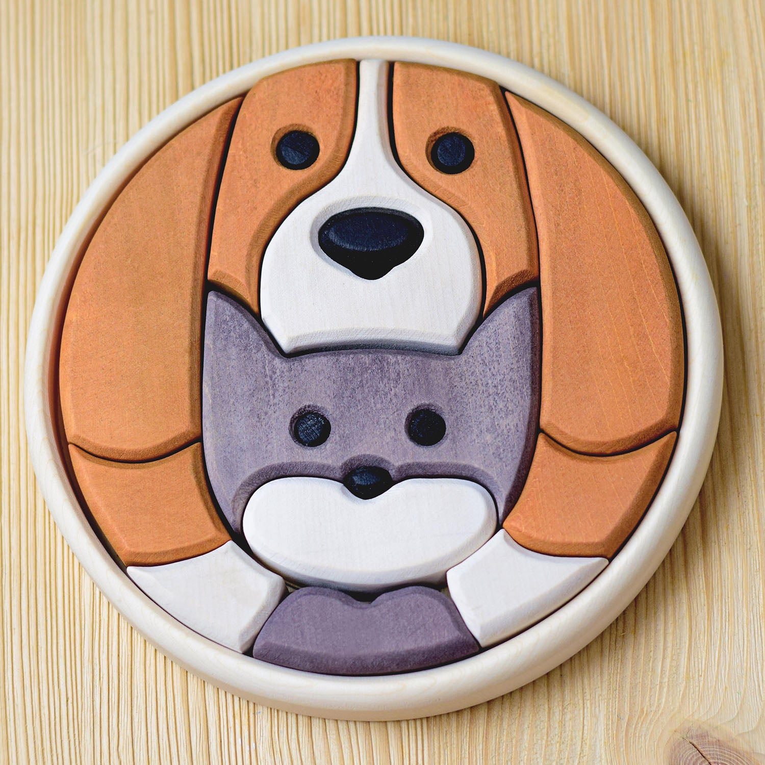 Bumbu wooden puzzle toy made of different wooden pieces to create the faces of a dog and a cat laid on a wood background.