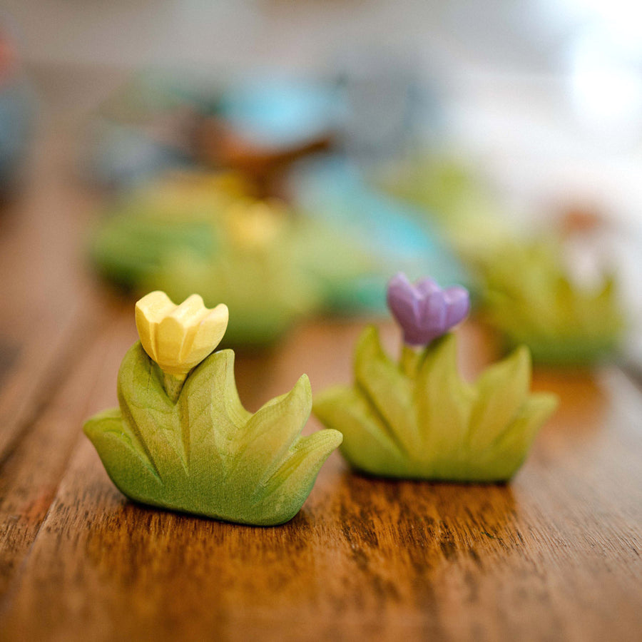 Close up of the Bumbu yellow and purple wooden grass and flower figures on a wooden worktop