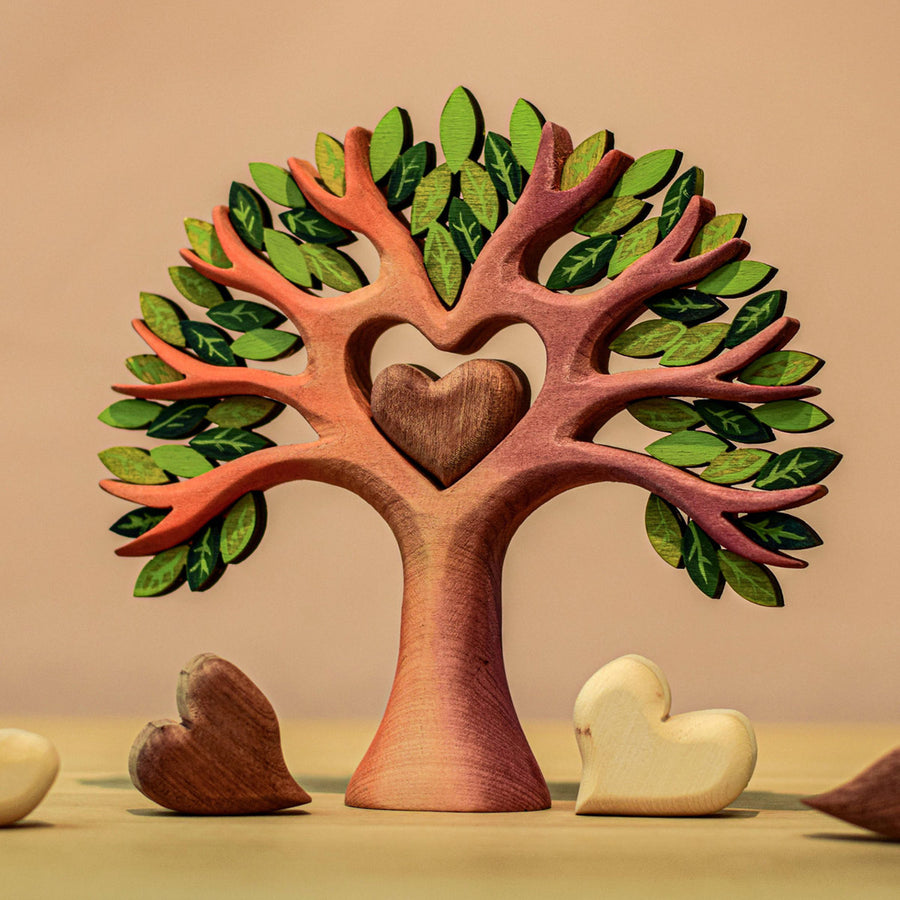 Two Bumbu Miniature Wooden peckers sit in the Bumbu Wooden Heart Tree. One is one top of the tree and the other is sitting in the heart cut out