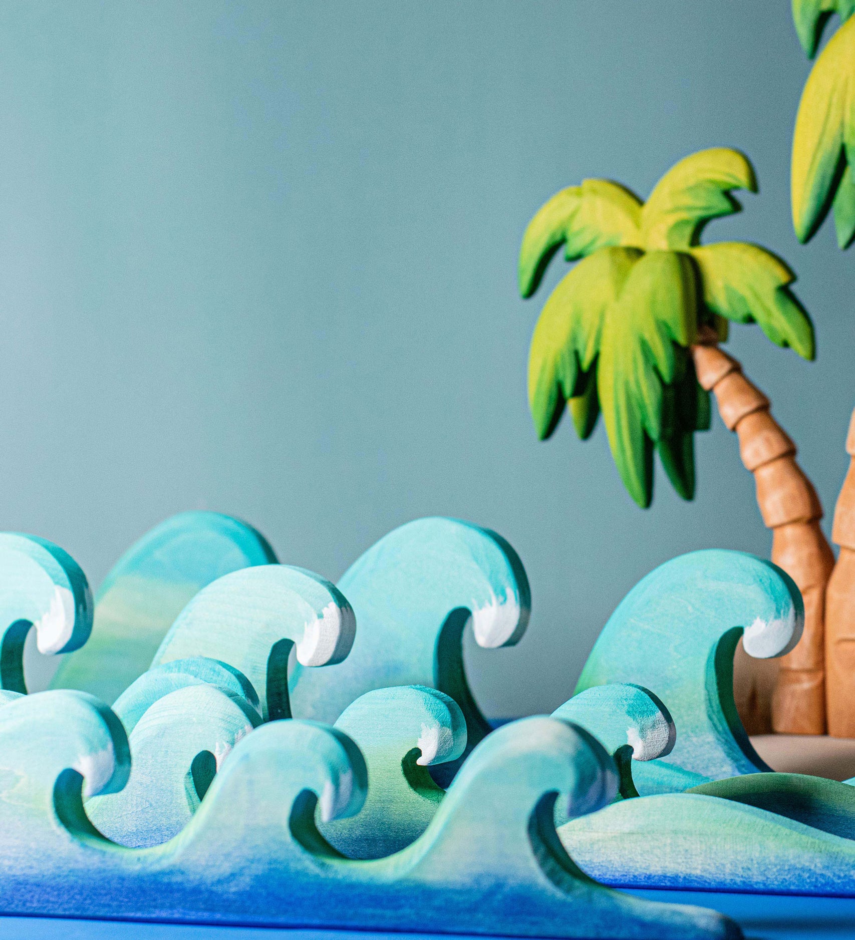 Bumbu waves wooden toys pictured with palm trees in the background.