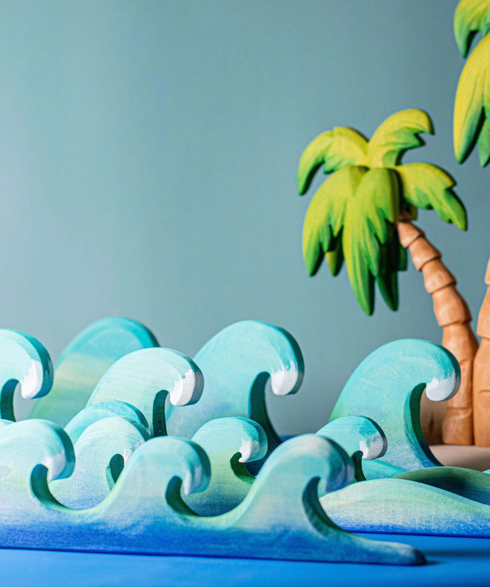 Bumbu waves wooden toys pictured with palm trees in the background.