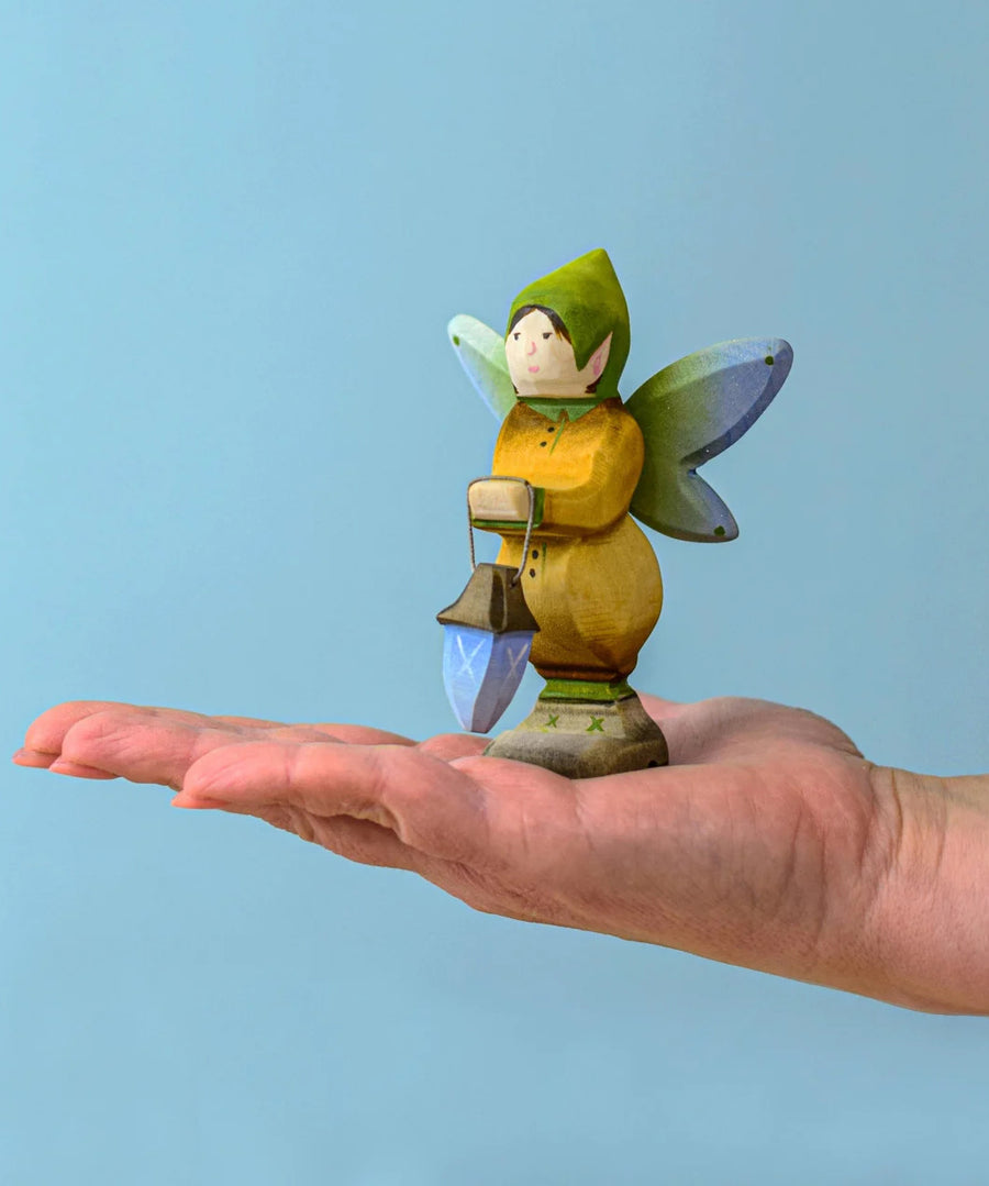 A Bumbu Wooden Winged Elf holding a mini lantern balancing on an adult's hand.