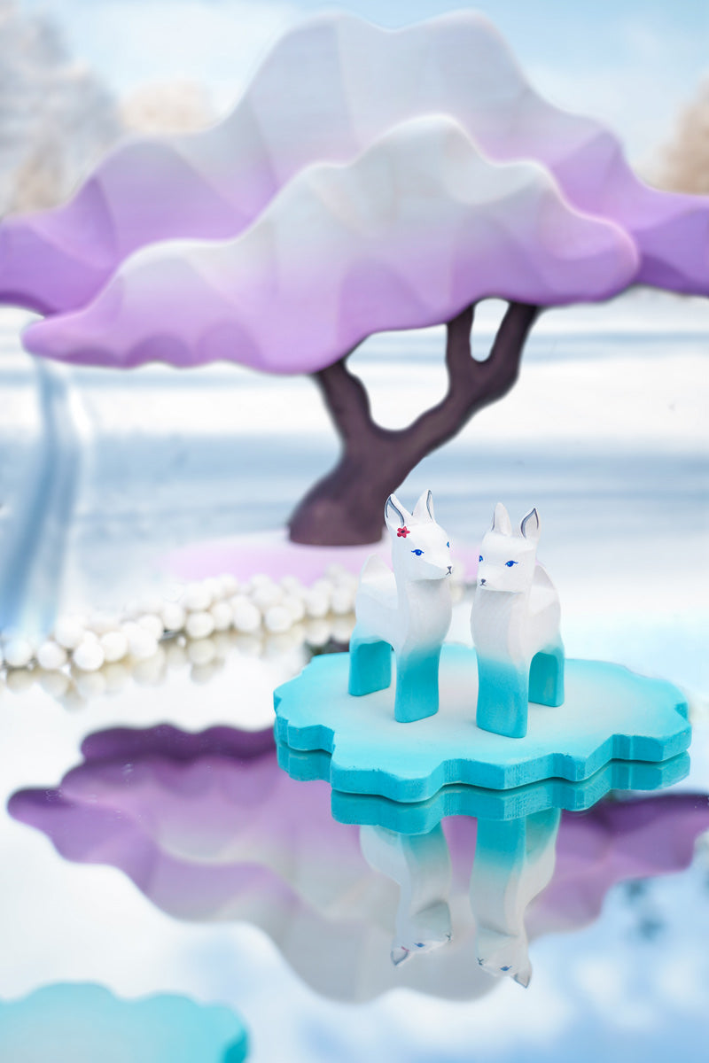 Two Bumbu wooden winter fawn figures stood on a Bumbu ice floe next to a winter maple tree toy