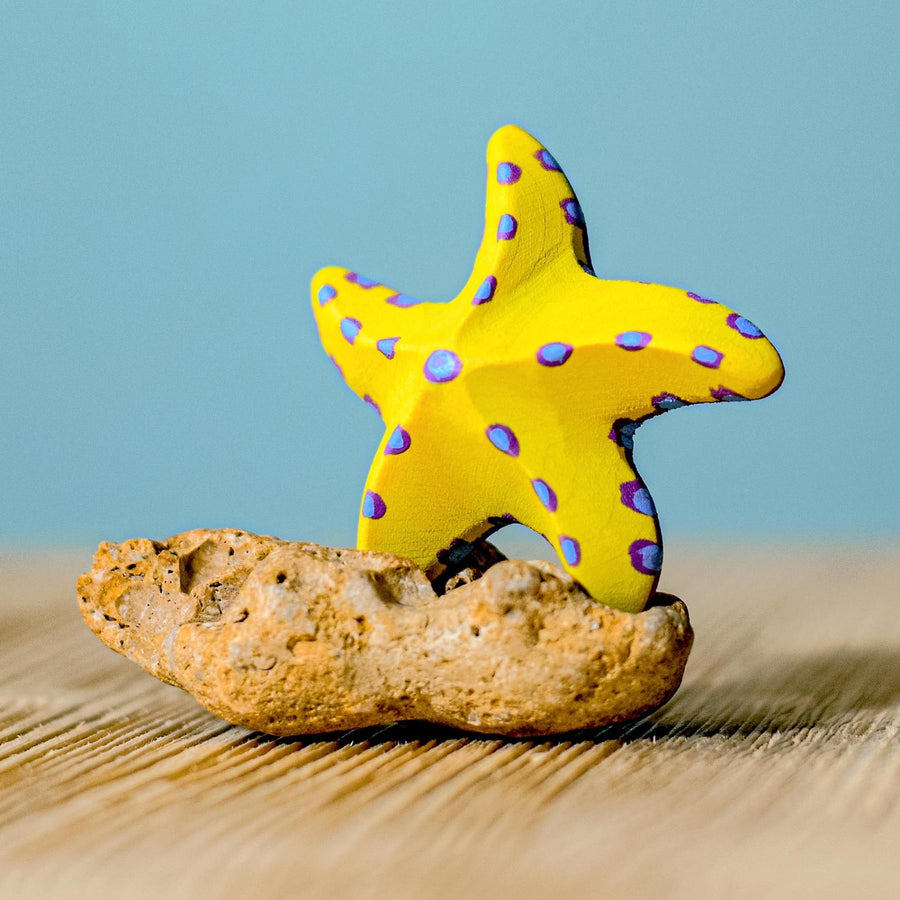 Bumbu wooden toy Yellow Starfish Set posed in a beach play scene.