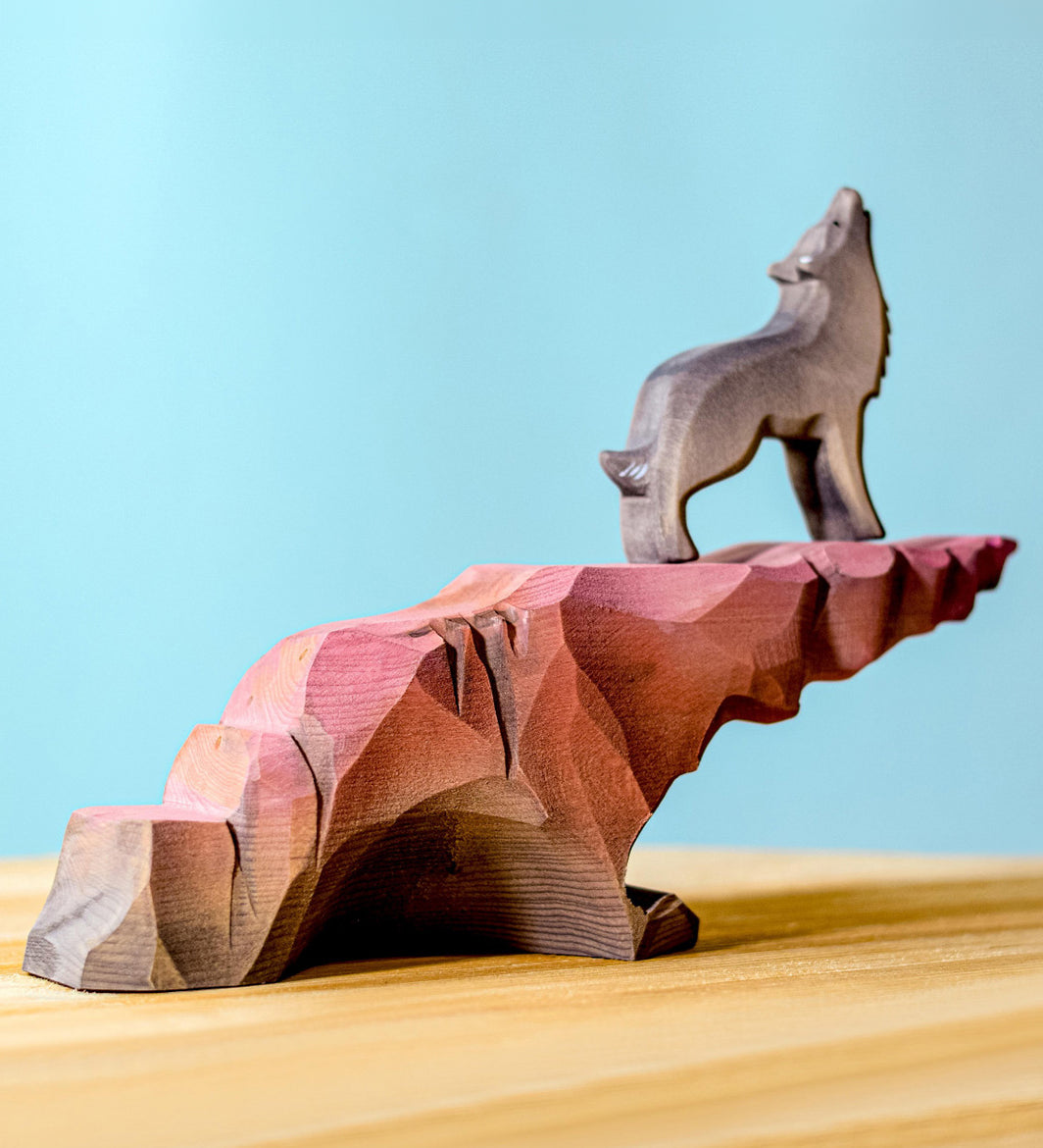 A wold stoof on top of a Bumbu wooden howling stone on a wooden surface against a blue background. 