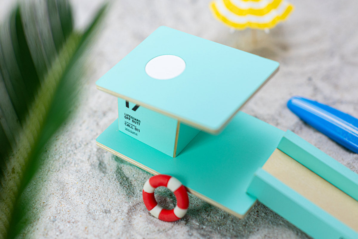 Close up of the Candylab teal beach tower model set on some sand next to some miniature umbrellas