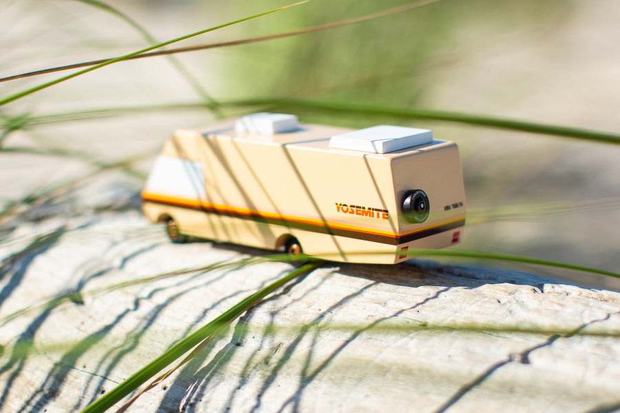 Close up of the Candylab yosemite campervan toy on some light wood behind some grass