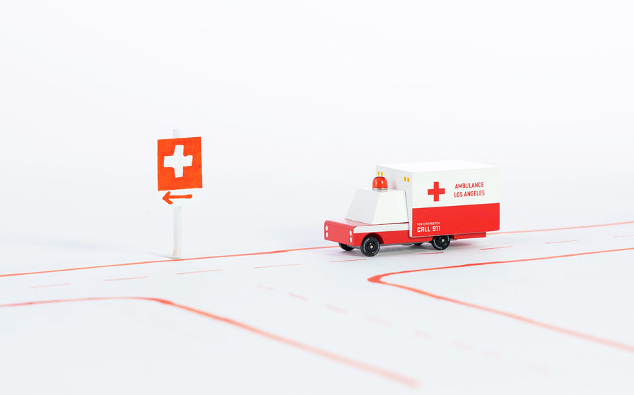 Candylab handmade wooden ambulance van toy on a red and white road layout