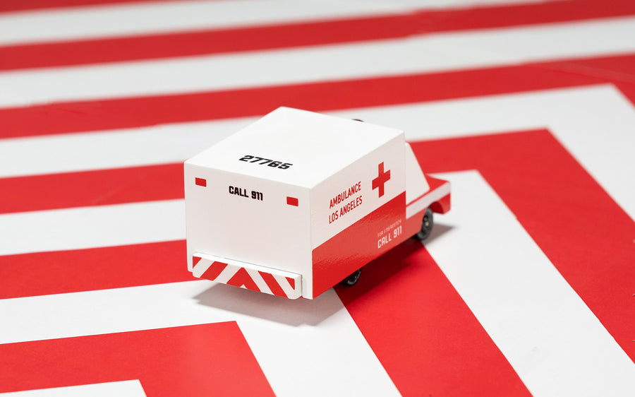 Candylab childrens small wooden ambulance toy on a red and white striped background