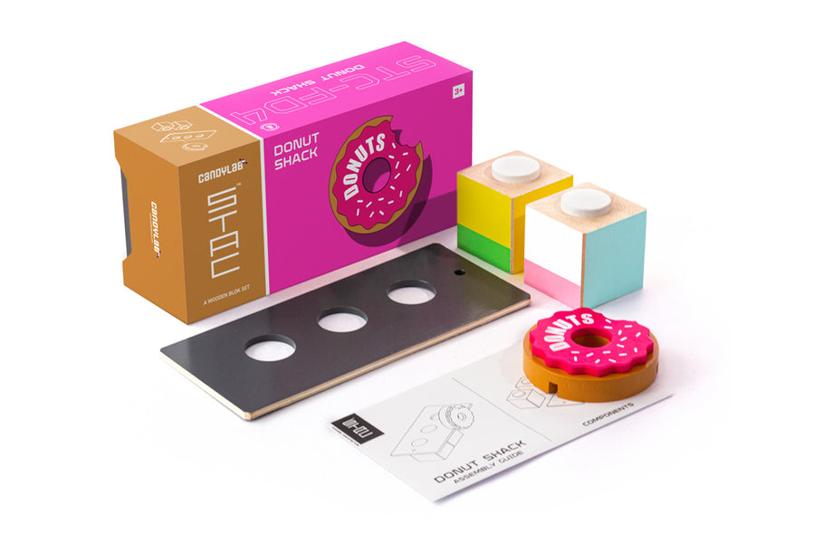 Pieces of the plastic-free Candylab donut shack collectable set on a white background next to the pink box