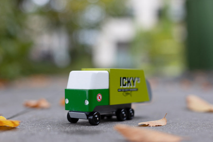 Close up of the Candylab toy garbage truck on the ground surrounded by fallen leaves