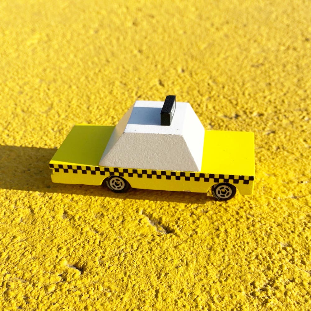 Close up of the Candylab handmade wooden taxi toy car on a yellow floor