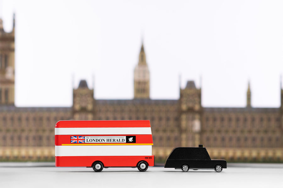 Candylab red double decker bus and black taxi car toys in front of a miniature Buckingham Palace