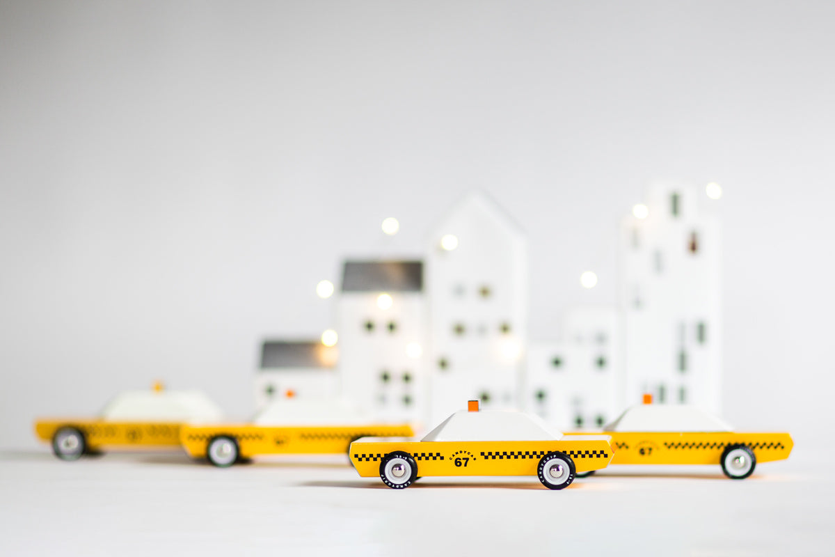 Candylab collectable wooden diecast car toys on a white background in front of some white toy houses