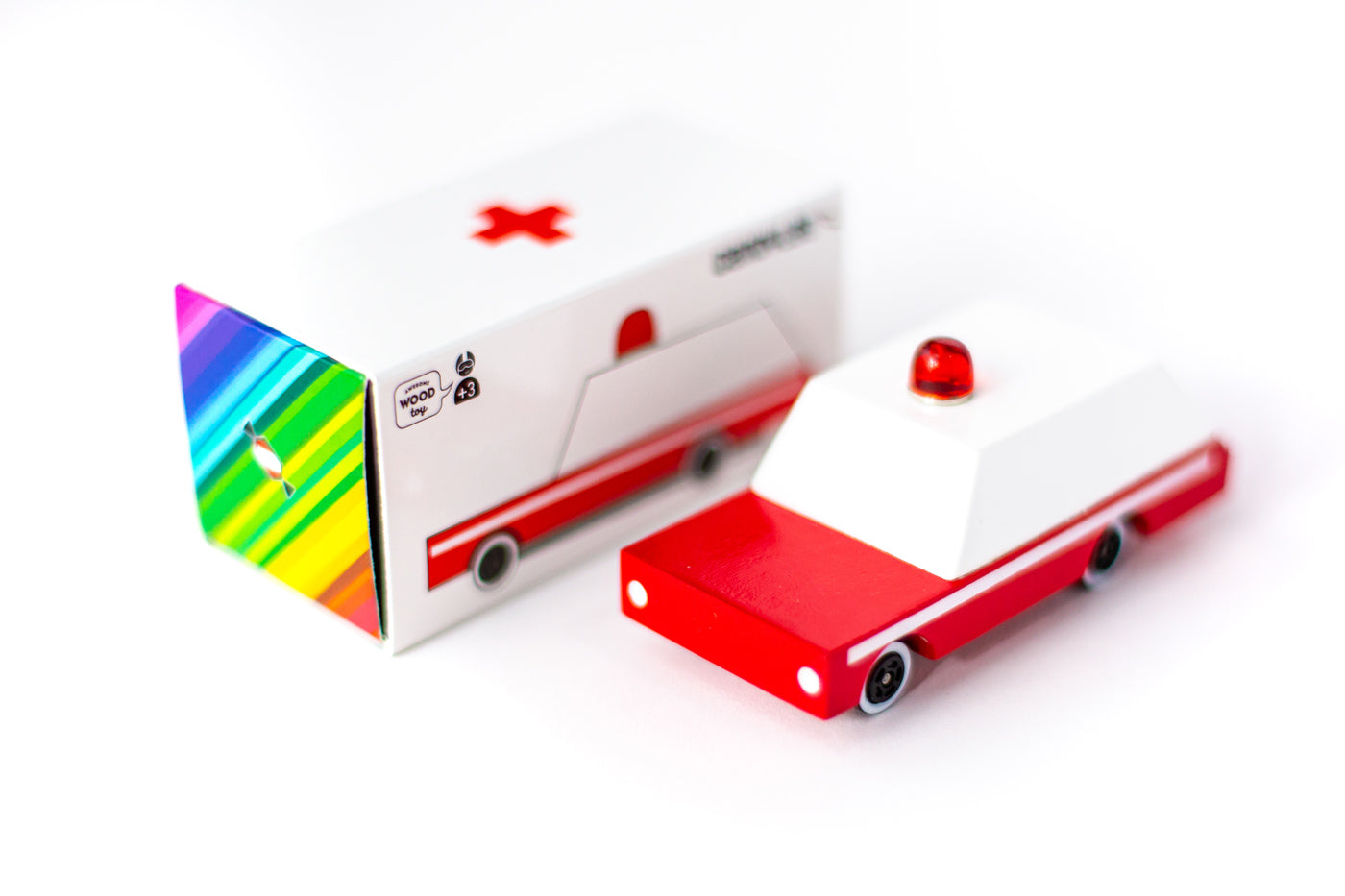 Candylab wooden ambulance toy on a white background next to its cardboard box