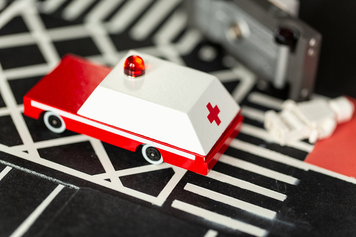 Close up of the Candylab solid wooden ambulance toy car on a black rubber road