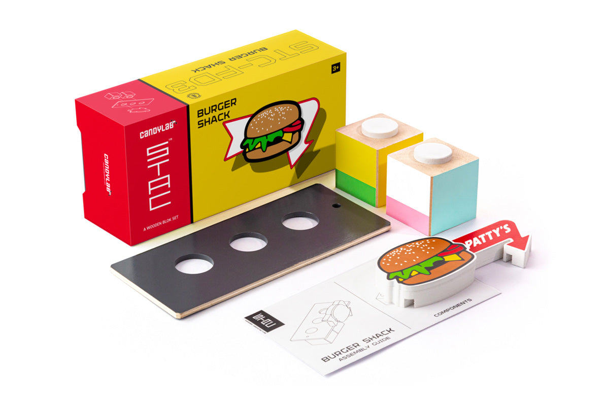 Pieces of the Candylab slotting wooden burger shack on a white background next to its cardboard box