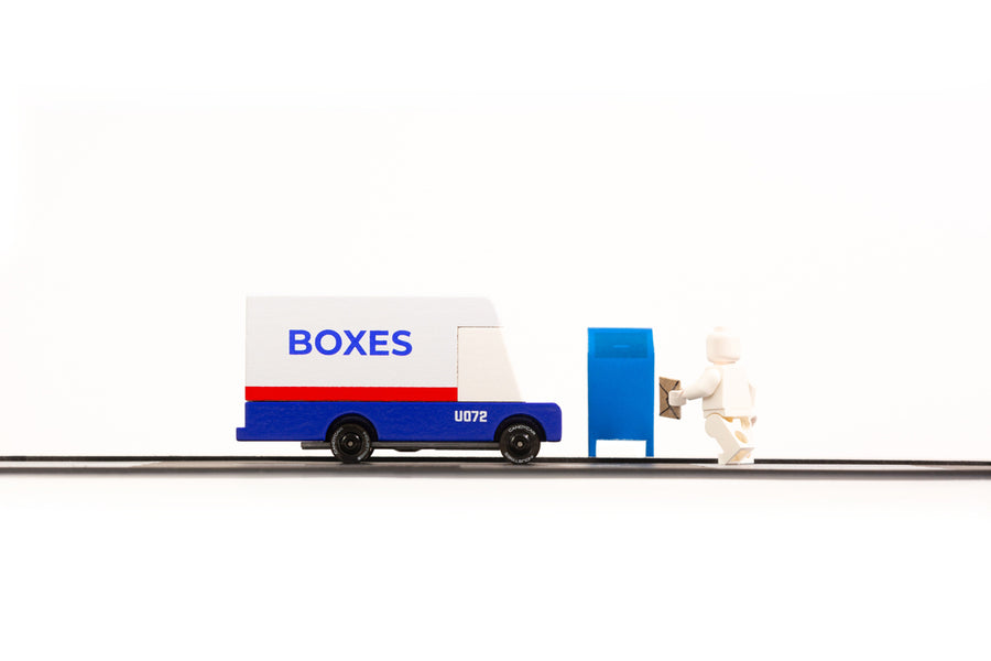 Candylab wooden diecast post van on a black rubber road next to a toy figure and mailbox toy