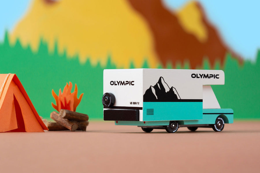 Close up of the Candylab collectable olympic rv toy on a brown background in front of a colourful mountain background