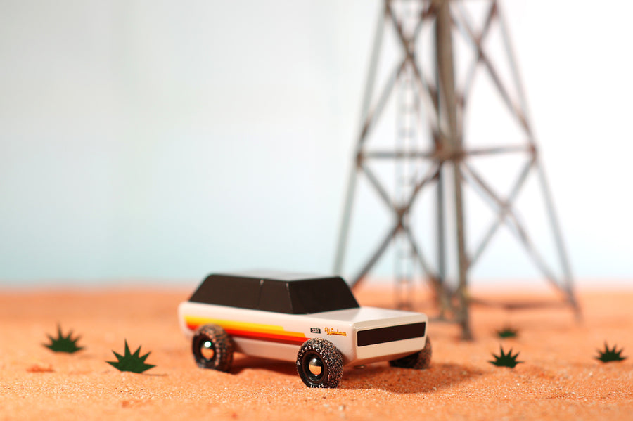 Candylab Wanderer SUV car toy on some orange sand next to a miniature tower