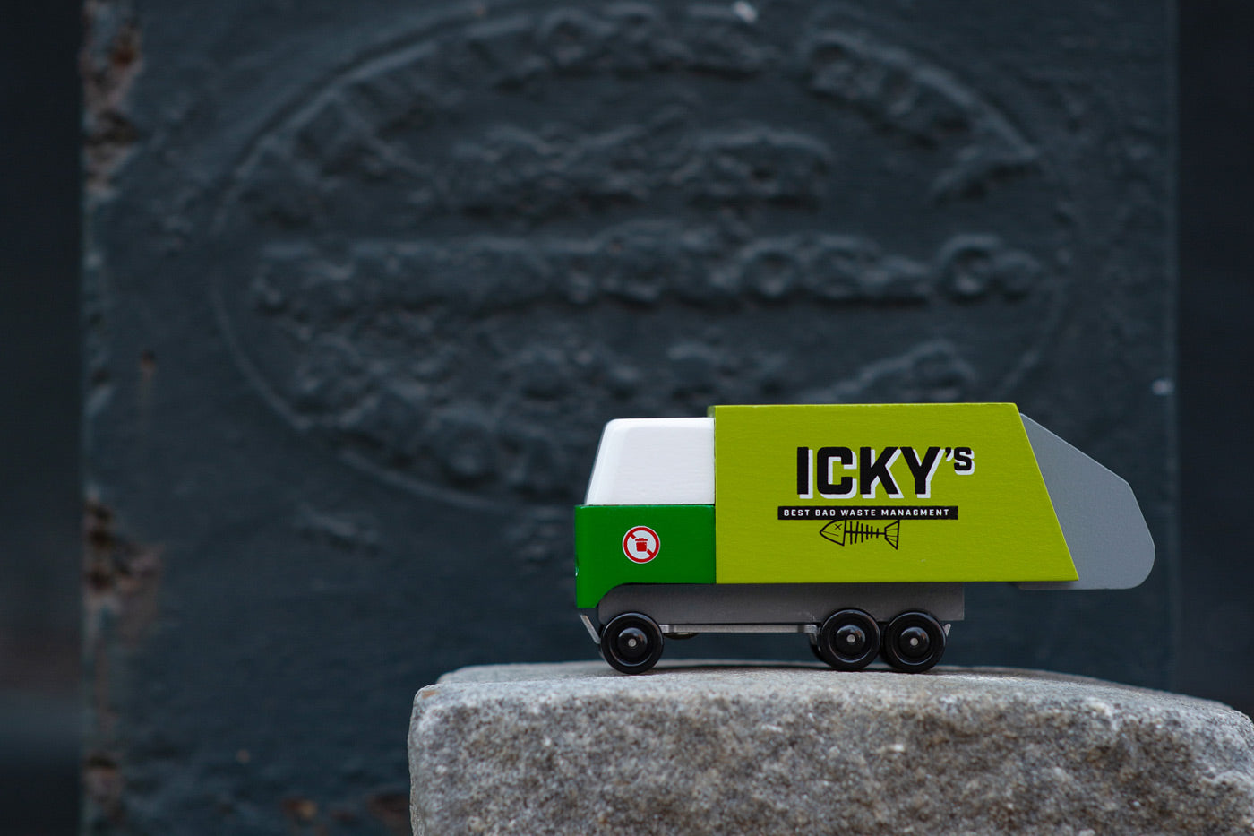 Close up of the Candylab Icky's garbage truck on a large stone in front of a dark grey wall