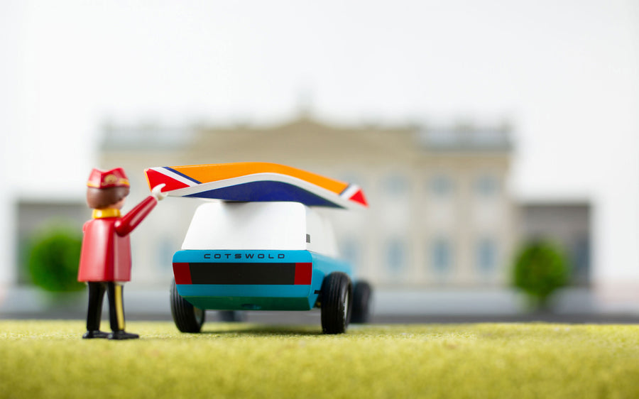 Close up of a toy figure putting the miniature wooden kayak on top of the Candylab blue suv toy