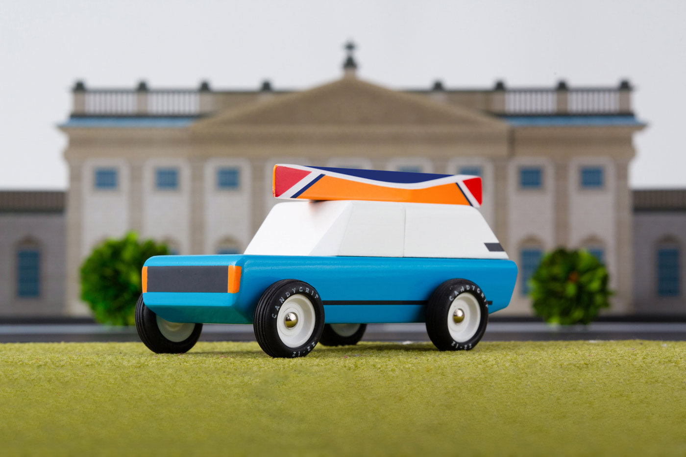 Candylab solid wooden cotswold royale toy car on a green background in front of a model palace