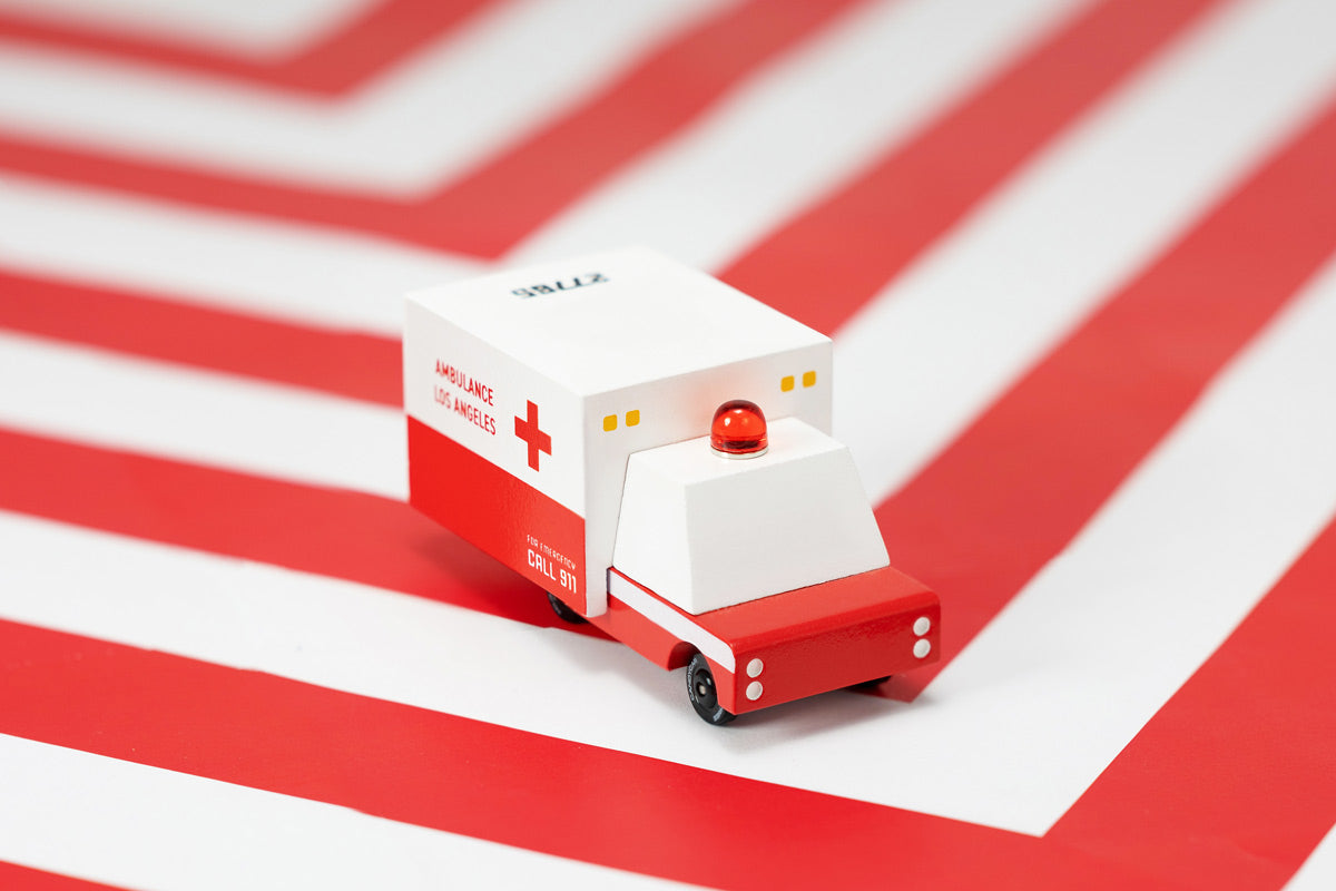 Candylab childrens small wooden ambulance toy on a red and white striped background