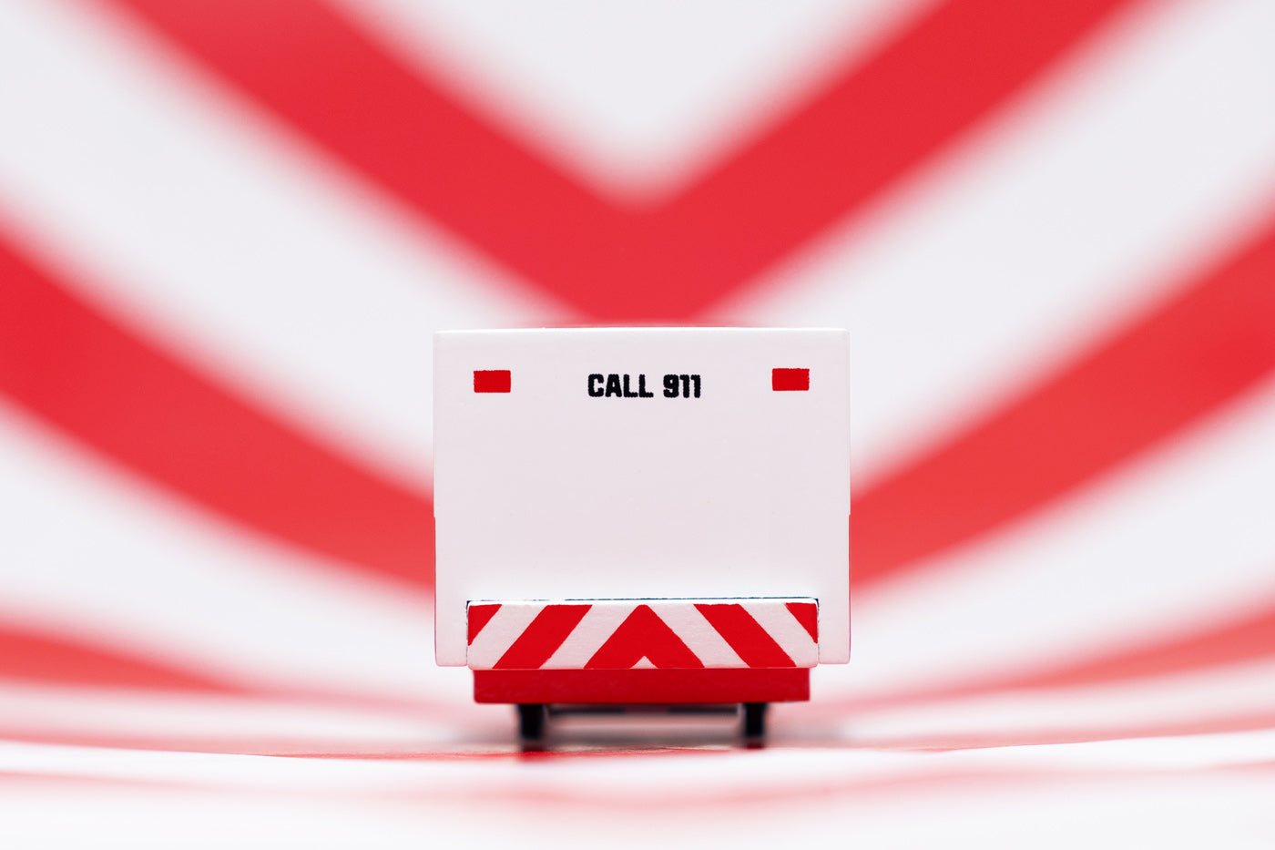 Close up of the back of the Candylab solid wooden ambulance van toy on a red and white striped background