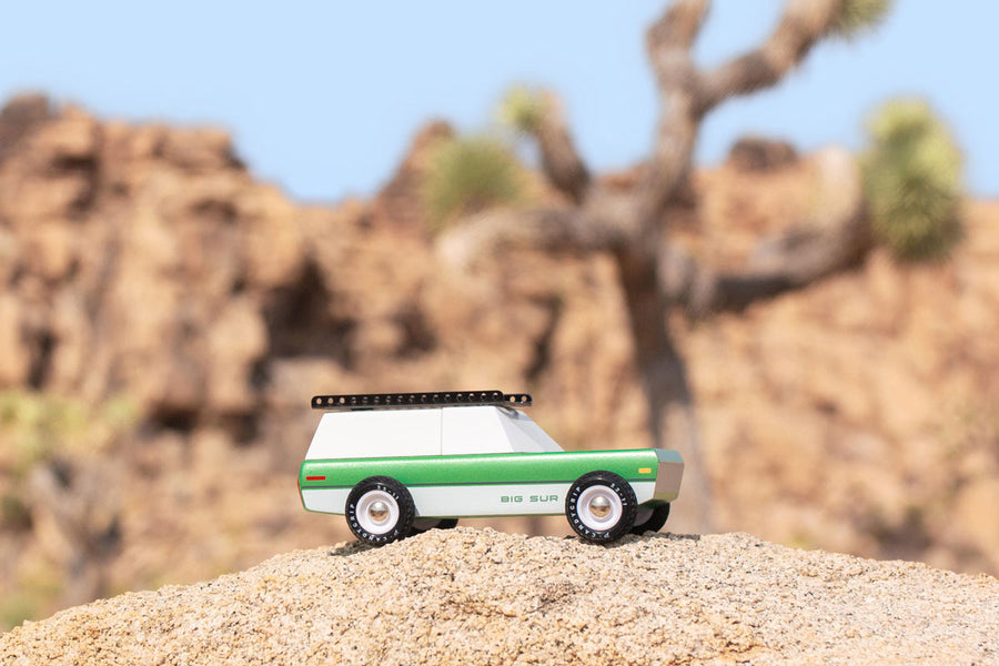 Side of the Candylab eco-friendly wooden big sur car toy on a large rock in front of a beige background