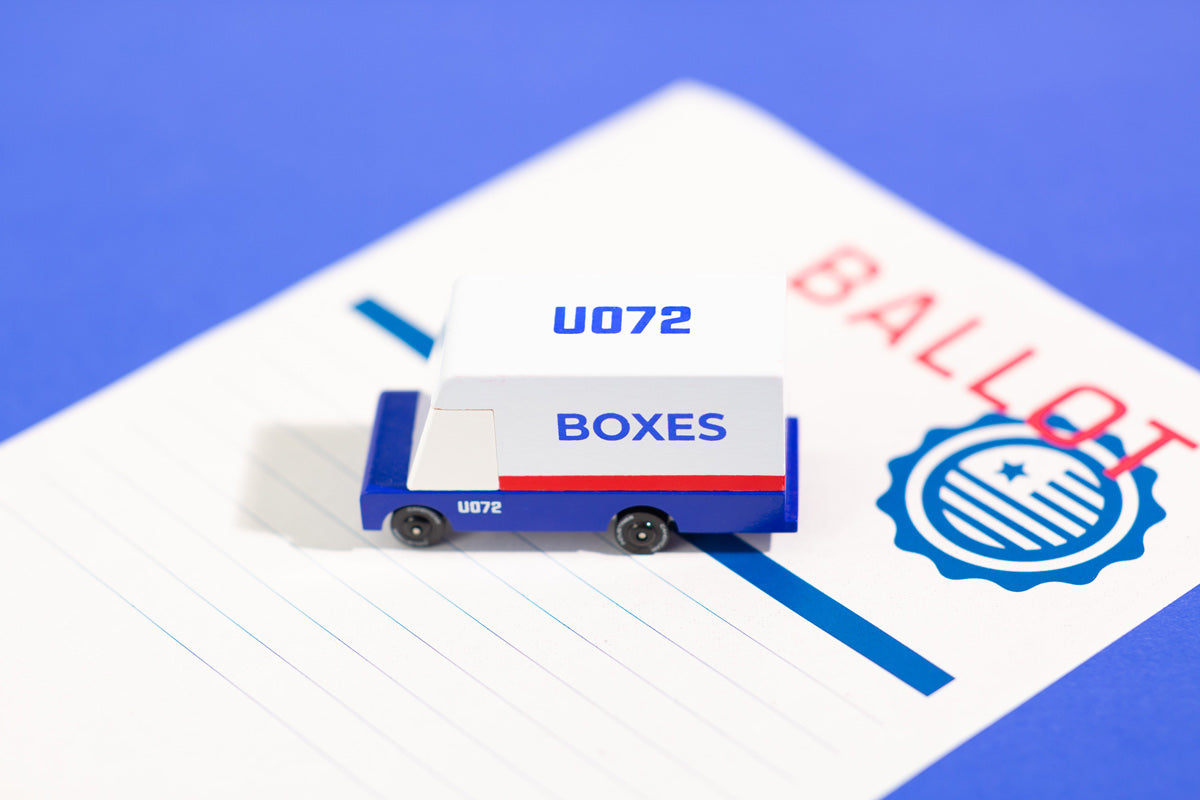 Close up of a Candylab wooden mail van toy on a blue ballot paper