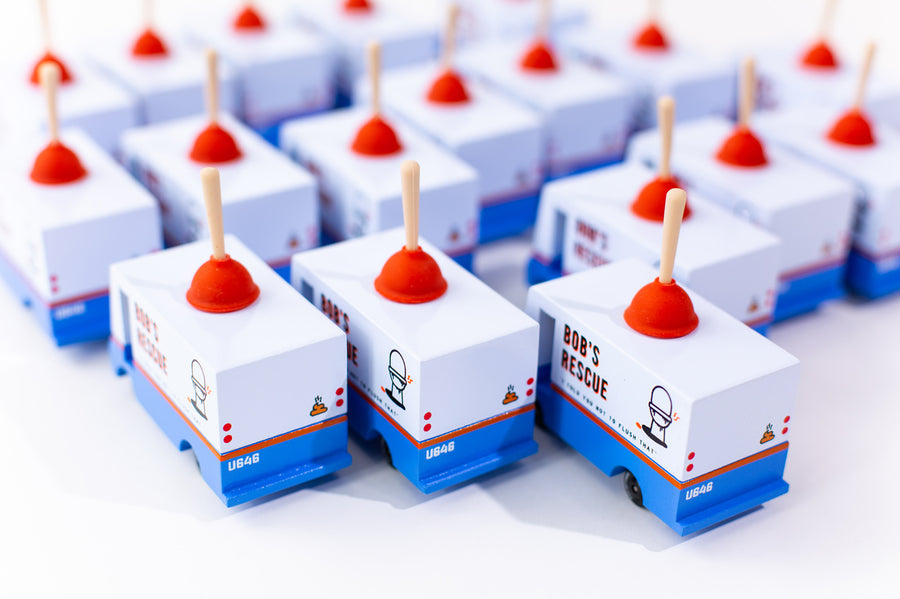 Group of Candylab handmade wooden plumbing truck toys lined up on a white background