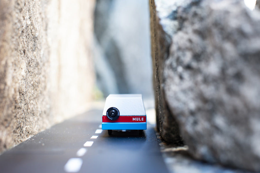 Candylab blue wooden mule car toy driving on a rubber road between two stones