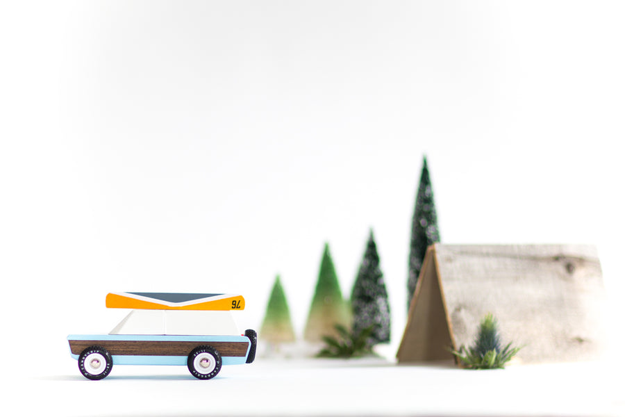 Side of the Candylab childrens blue car toy on a white background in front of some small tree and tent toys