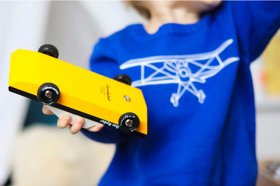 Close up of a child holding a Candylab Doc Ryder yellow and black muscle car toy