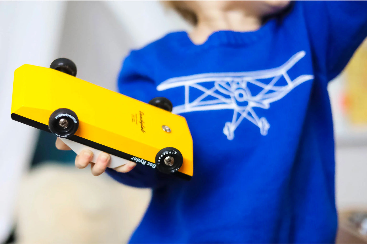 Close up of a child holding a Candylab Doc Ryder yellow and black muscle car toy