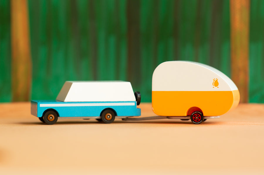 Candylab kids wooden blue mule car toy with the rosebud toy trailer attached on an orange and green background