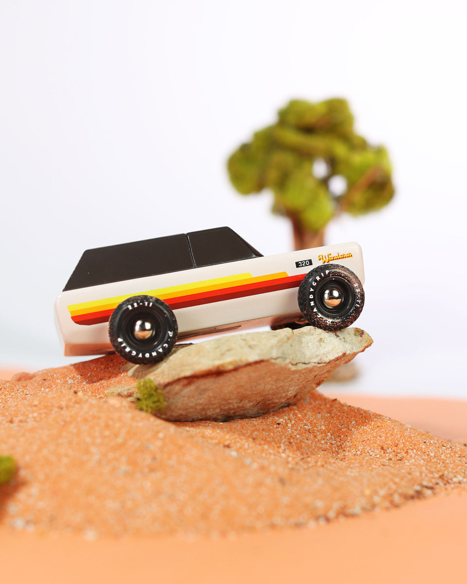 Close up of the Candylab wooden range rover car toy in some sand on a miniature desert scene