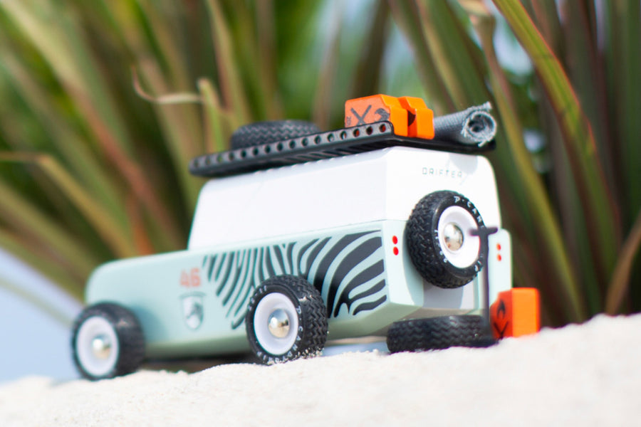 Back of the Candylab childrens wooden zebra drifter suv toy on some sand next to its spare tyre