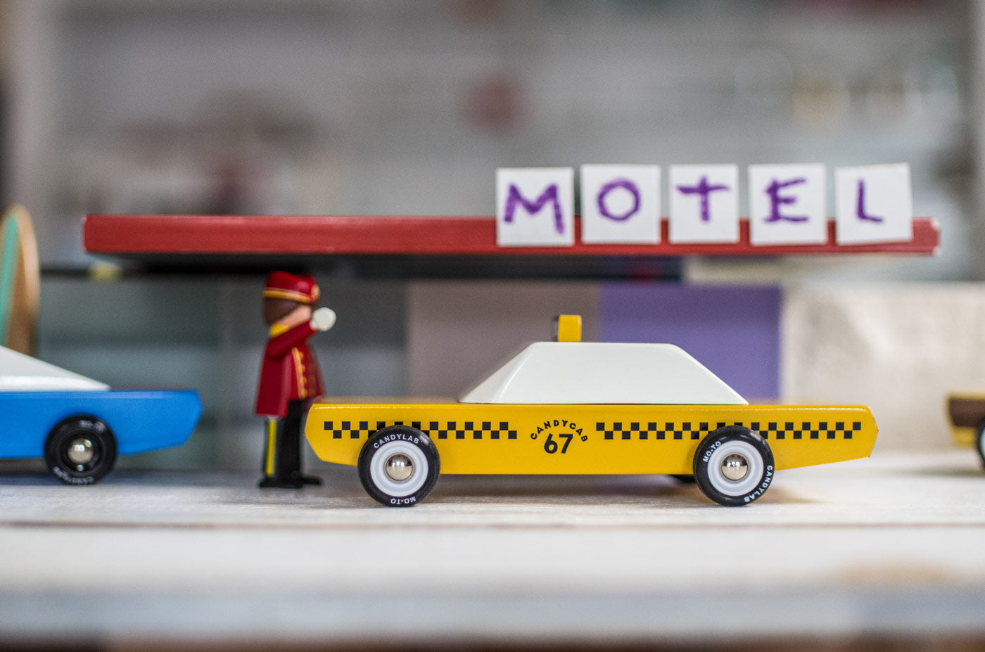 Close up of a Candylab children diecast taxi car in front of a toy motel