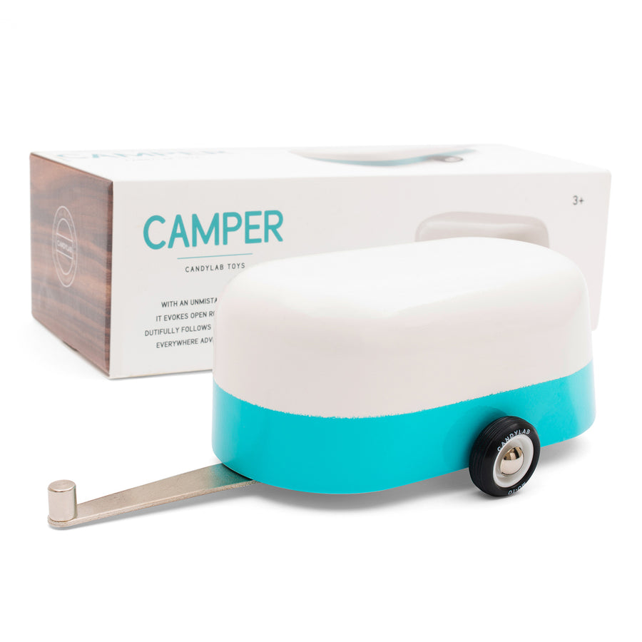 Candylab kids handmade wooden blue caravan toy on a white background in front of its cardboard box