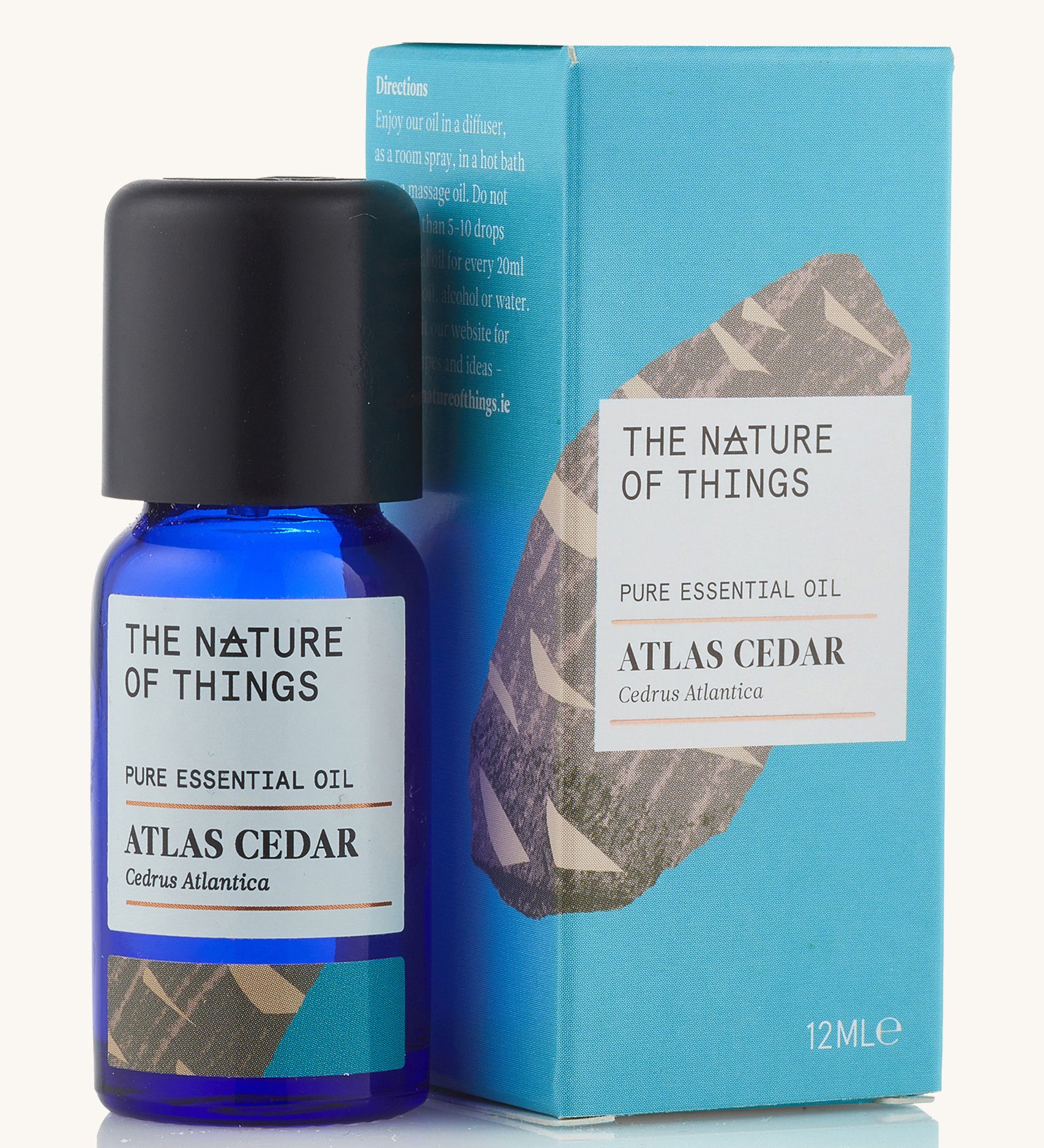 Atlas Cedar pure essential oil in a blue glass bottle in front of a decorative blue cardboard box. 