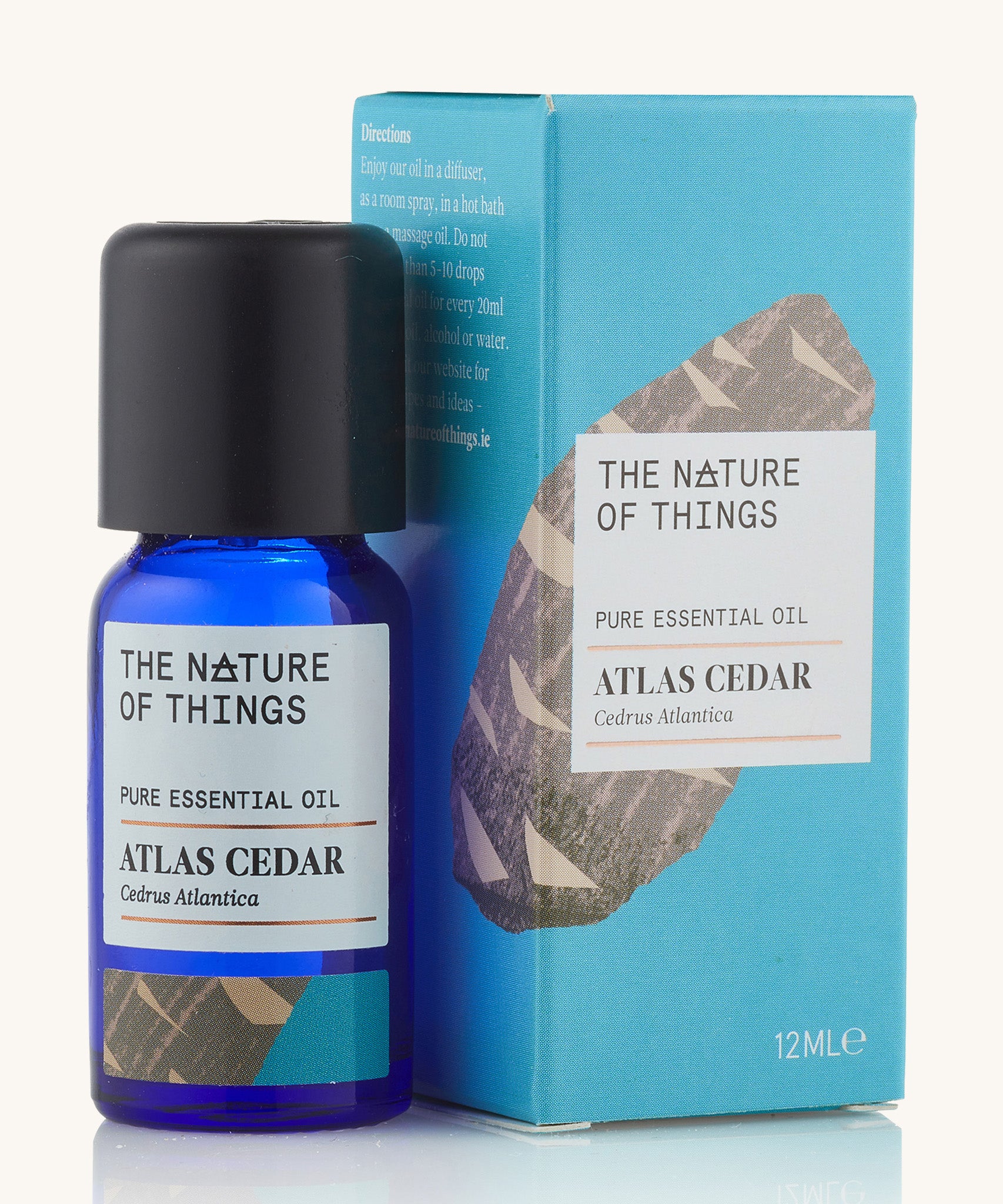 Atlas Cedar pure essential oil in a blue glass bottle in front of a decorative blue cardboard box. 