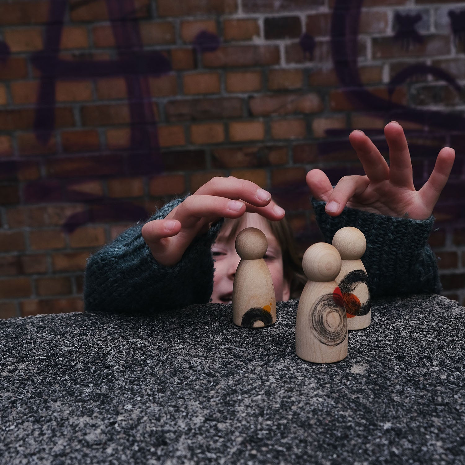 Close up of child playing with 3 Grapat Waldorf peg doll toys