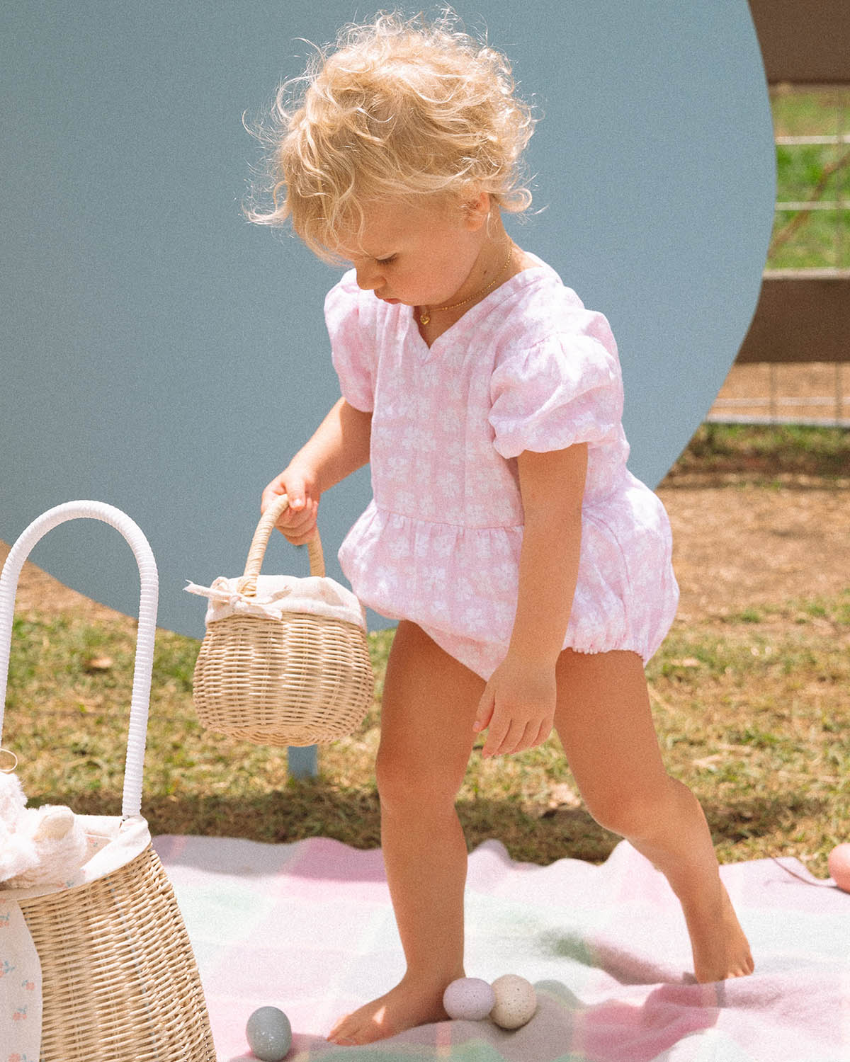 Two children holding the Olli Ella Rattan Berry Basket with Lining – Pansy Floral and Gumdrop in their hands. Inside each basket are colourful pink