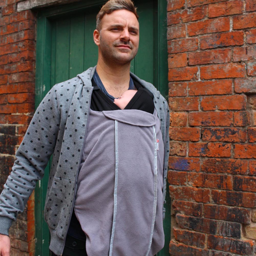 Man stood in front of a brick wall wearing the close caboo baby carrier fleece cocoon liner