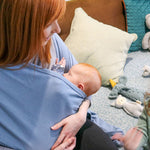 Close up of woman holding a baby in the close caboo lite baby carrier in the denim blue colour