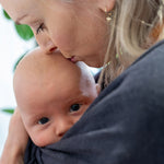 Close up of woman stood wearing the close caboo lite baby carrier in the nightfall colour